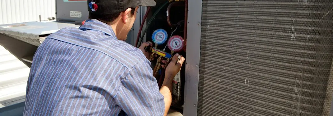 HVAC technician servicing a condenser unit in Jonesboro